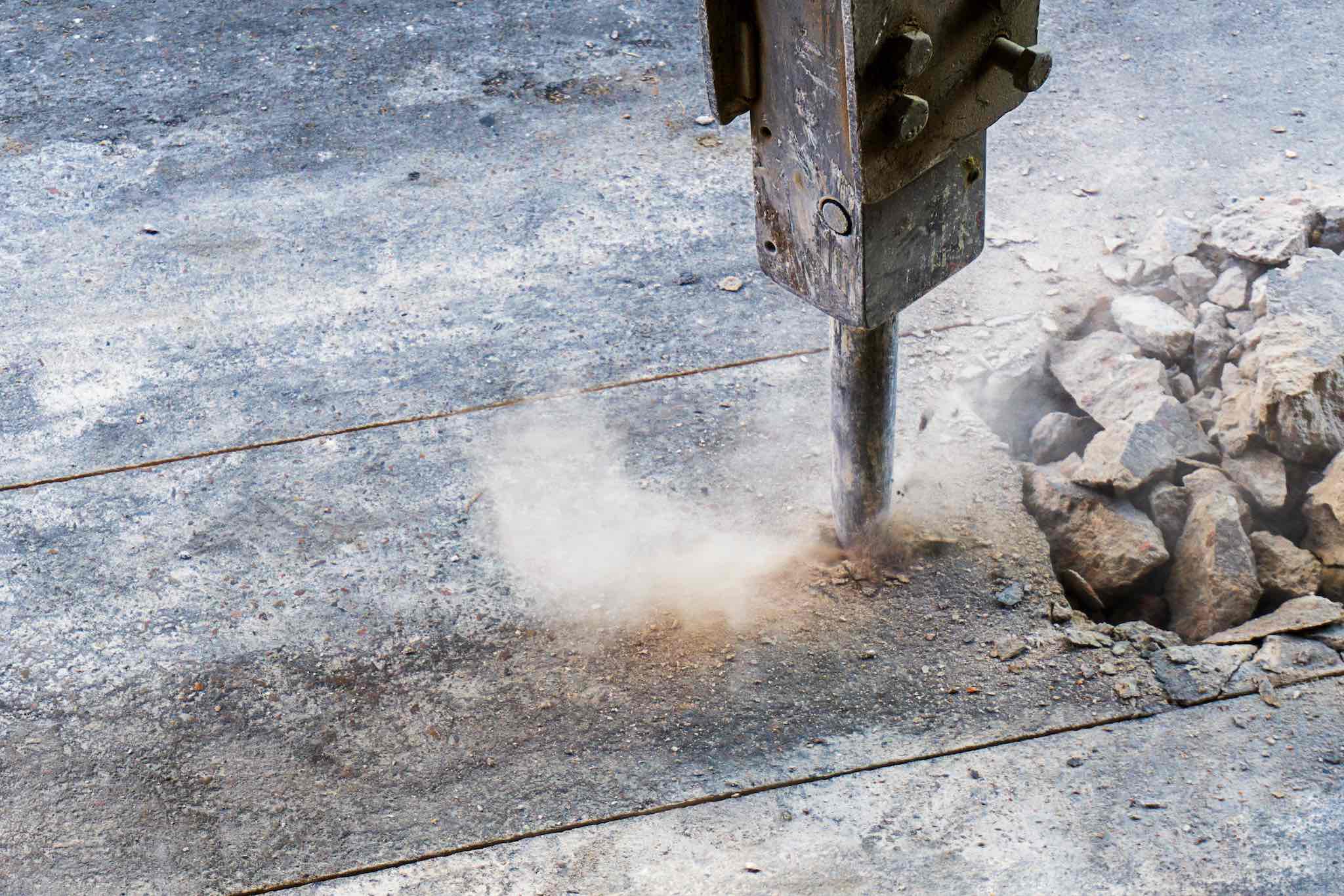 Excavator hydraulic  jack hammer is breaking concrete road prepare for water piping system work